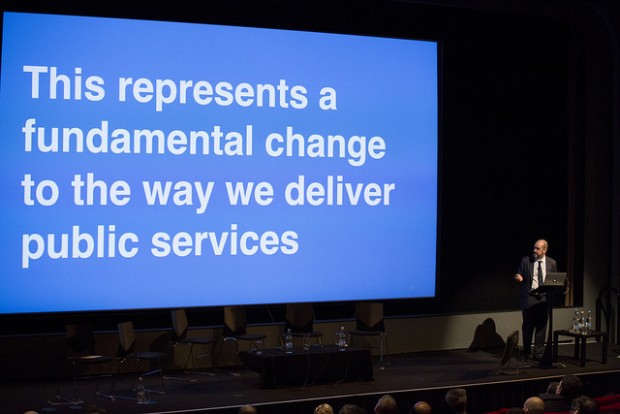 Mike Bracken on stage at Sprint 15, in front of a large slide saying “This represents a fundamental change to the way we deliver public services”