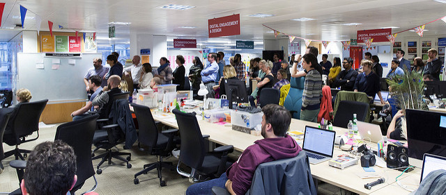 Photo of GDS team listening to an impromptu talk in the Aviation House offices. Bunting, macbooks, signage.