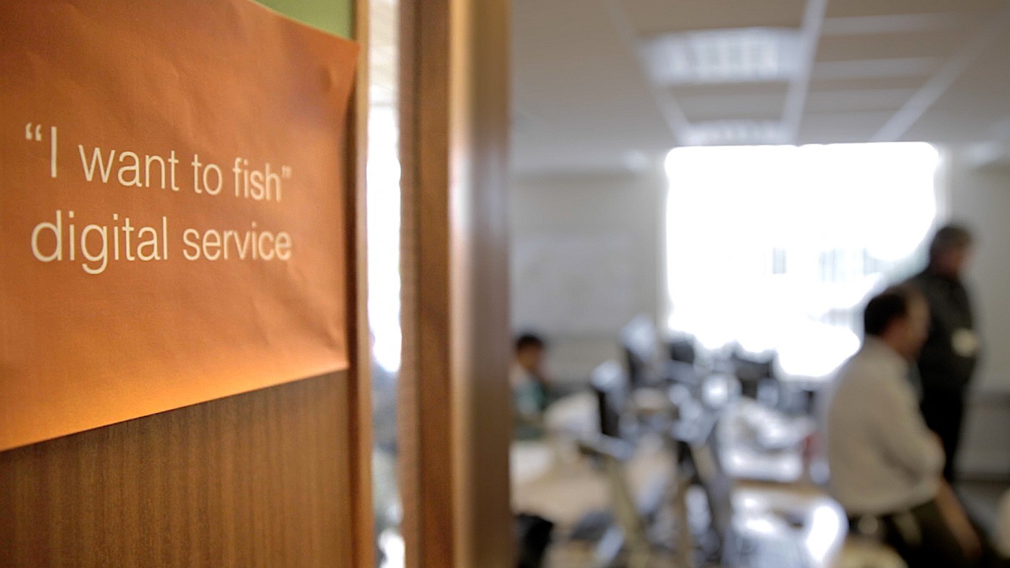 Poster on a door - "I want to fish: digital service" - blurred office scene in background