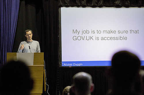 Photo of Alistair Duggin speaking at a GDS all staff event - slide reads "My job is to make sure GOV.UK is accessible"