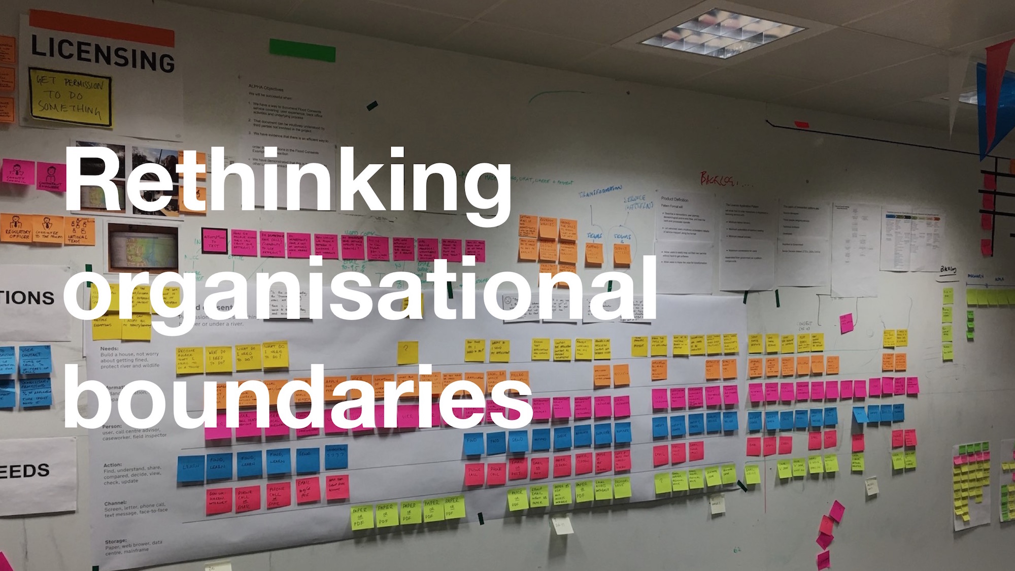 Photo of GDS wall with post it notes, overlaid with the text "Rethinking organisational boundaries"