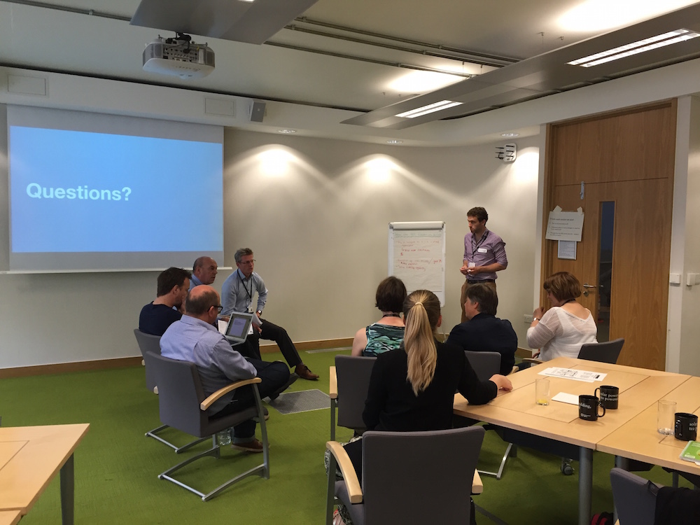 Breakout Group - people sat together in front of board that says 'Questions?'