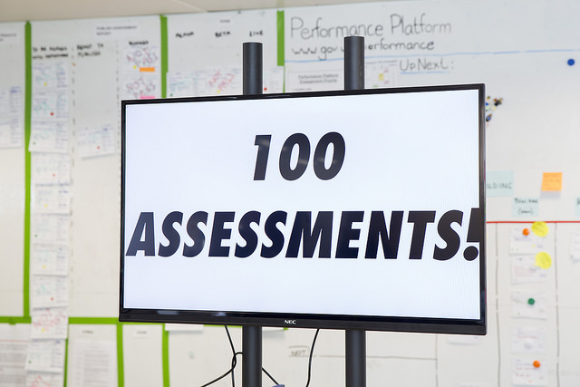 A screen in the GDS office with the words “100 assessments!”