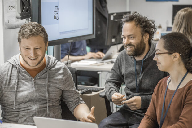 3 members of staff sitting together and looking at a laptop