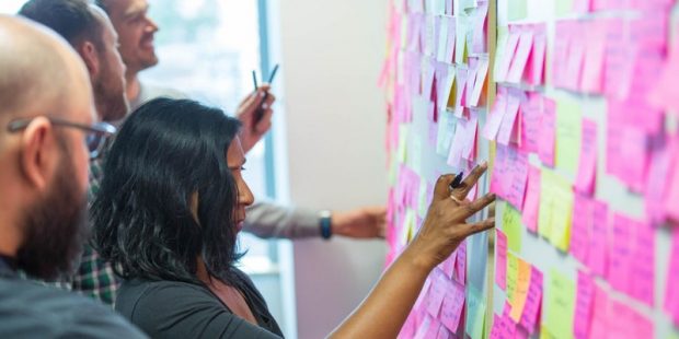 Digital Marketplace team members in front of a board with post-it notes