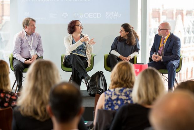 a panel of 4 people on a stage, discussing something