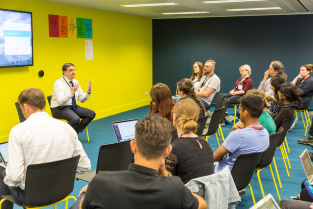 Rupert McNeil, Chief People Officer for the Civil Service speaking at GDS, and a group of people listening to the talk