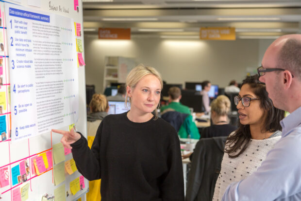 policy team standup with a poster of the framework principles in the background