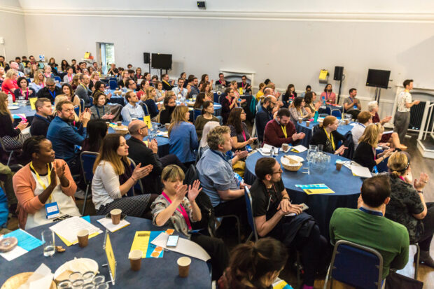 ConCon participants sitting around tables and listening to a talk