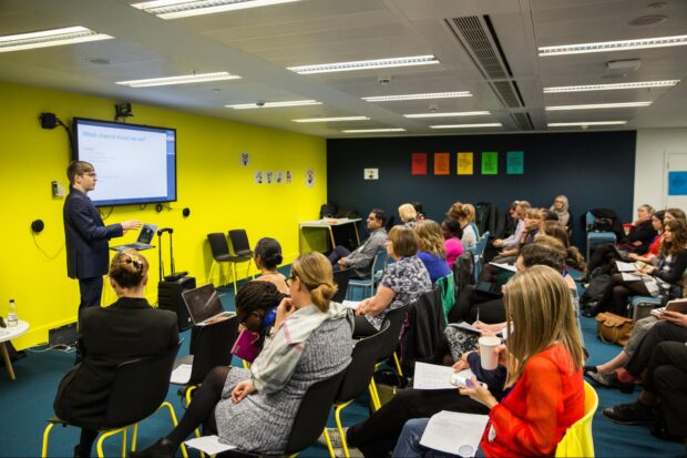 A room full of people listening to a presenter