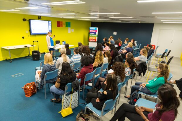 A room full of people listening to a presentation