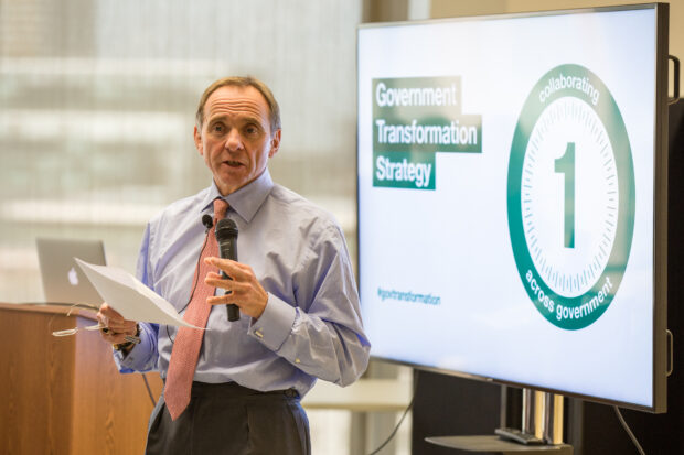 John Manzoni in front of a screen that says 'Government Transformation Strategy', speaking to GDS staff