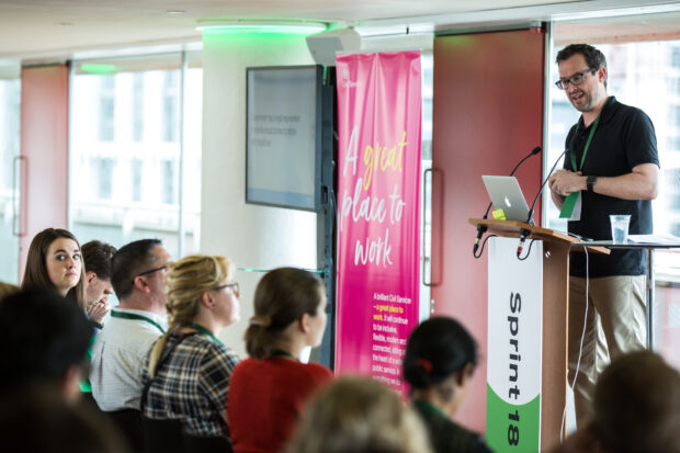 Presenter speaking, front row of people shown