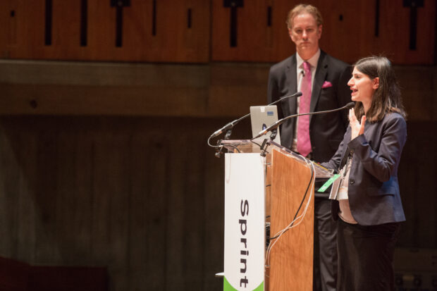 Two People and skills workshop presenters at Sprint 18, standing at a lectern, one of them speaking