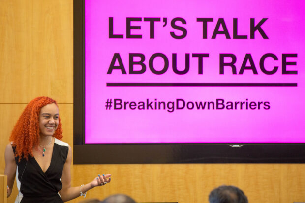 An image of GDS's Tia Priest at the event standing in front of a screen saying: Let's Talk About Race