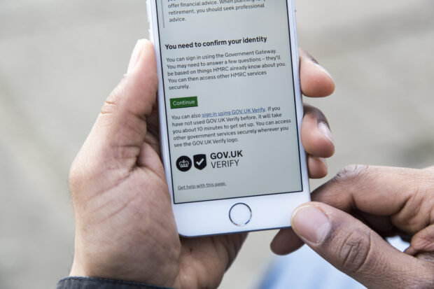 A mobile phone using an HMRC service which requires the user to confirm their identity. The text reads: You can also sign in using GOV.UK Verify. If you have not used GOV.UK Verify before, it will take about 10 minutes to get set up. You can access other government services securely wherever you see the GOV.UK Verify logo."