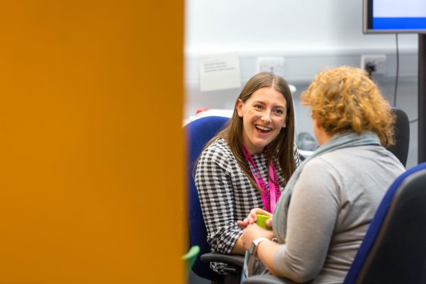 Two people participating in the Speed Mentoring event. One's back is to the camera, the other is facing the camera and smiling