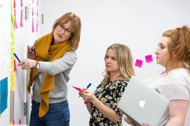 3 members of the unconference team planning in front of a wall covered with post-it notes