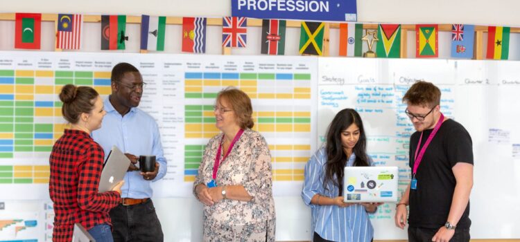 5 people standing in front of a board with a roadmap on it and a sign saying 'DDaT Profession'