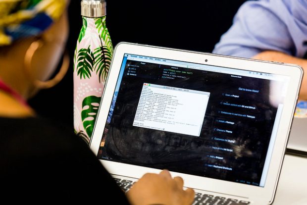 a computer screen with code, and a user typing on the keyboard