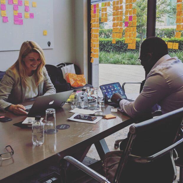 two people sitting at a table with their laptops