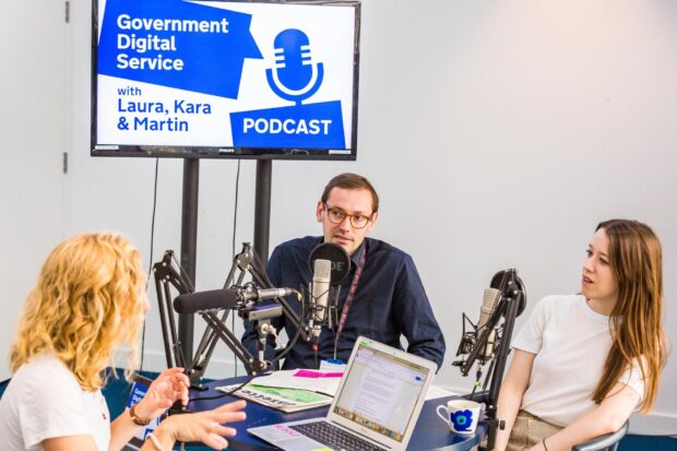 the interviewer and 2 interviewees in the recording studio, the screen behind the says 'Government Digital Service podcast, with Laura, Kara and Martin'