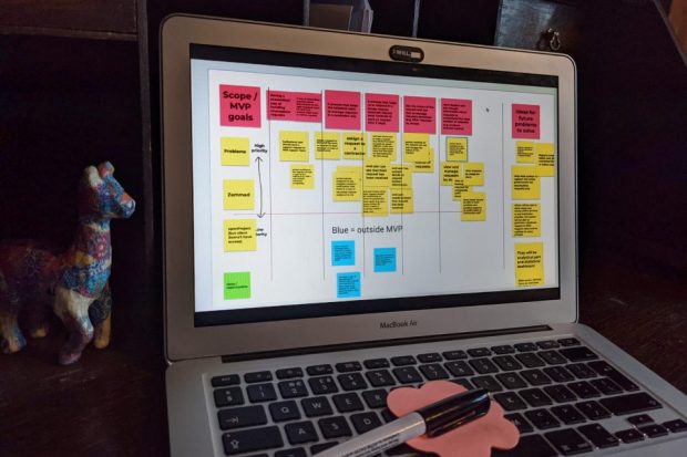 A digital collaborative board with notes outlining scope or minimum viable product goals, and sorting them into a spectrum ranging from high to low priority. Blue notes fall outside of the minimum viable product. There are also notes showing ideas for future problems to solve.