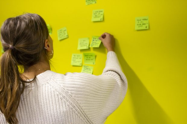 A person placing sticky notes on a wall.