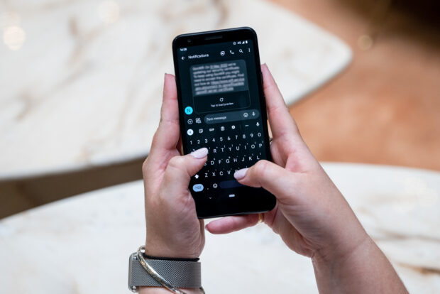 A person's hands are holding a smartphone with a notification text on the screen.