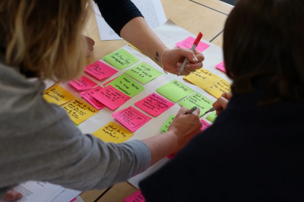 People working together, writing on colourful post-it notes.