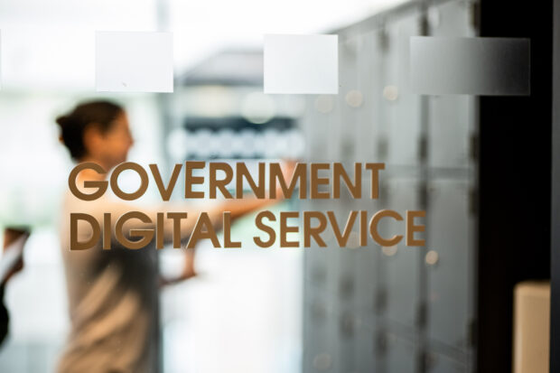Government Digital Service text on an office window with a person in the background