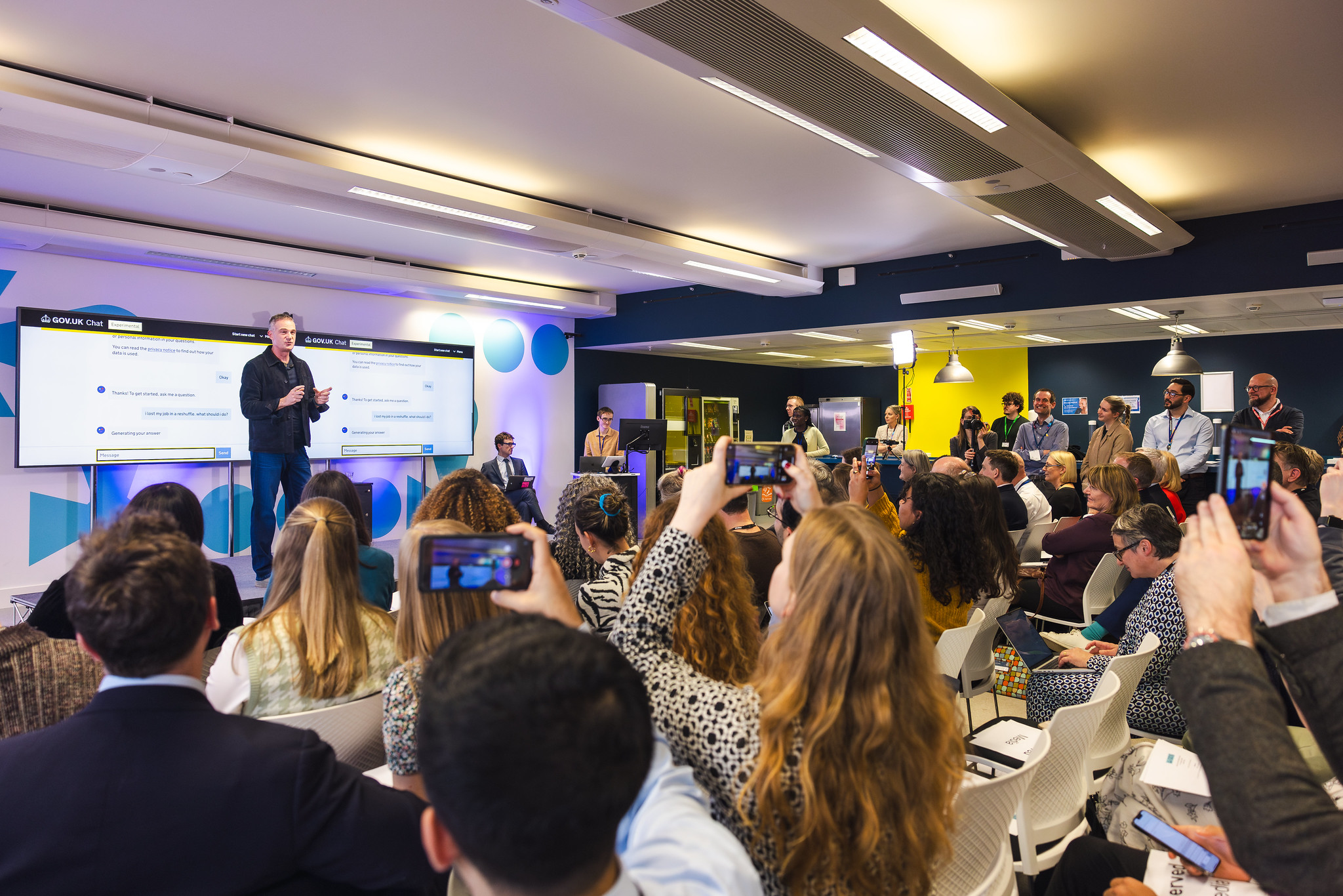 Photo from Digital Centre launch event showing DSIT's Secretary of State, Peter Kyle on stage presenting the new GOV.UK chatbot to audience.