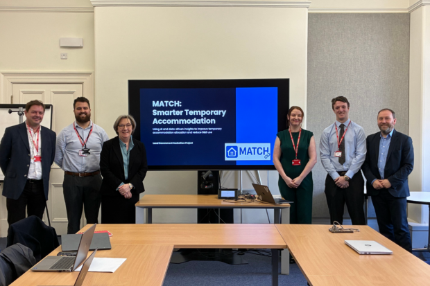Four members of ‘Team Match’, the winners of the Hackathon, stand with Minister Dixon (MHCLG) and Minister Murray (DSIT) in front of the presentation that they delivered to them.