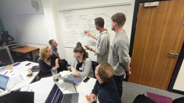 A group of colleagues brainstorming around a white board